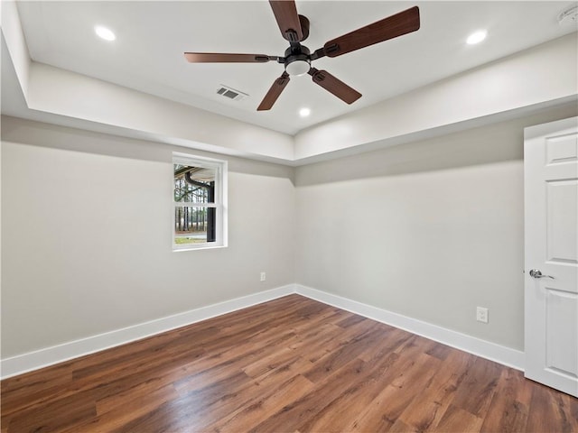 empty room featuring dark wood-style floors, recessed lighting, visible vents, and baseboards