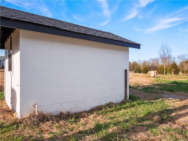 view of property exterior with concrete block siding and roof with shingles