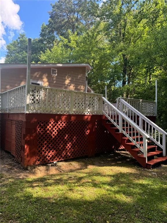 rear view of house featuring stairs, a lawn, and a deck