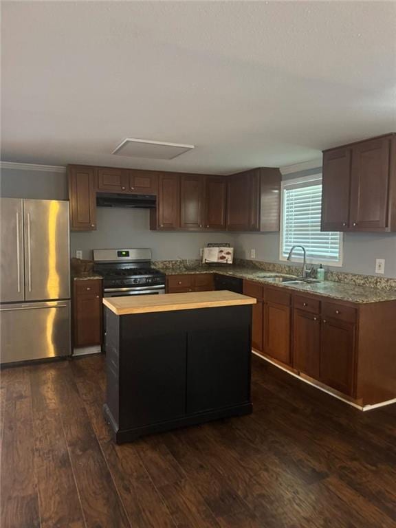 kitchen featuring stainless steel appliances, under cabinet range hood, a sink, dark wood-style floors, and a center island