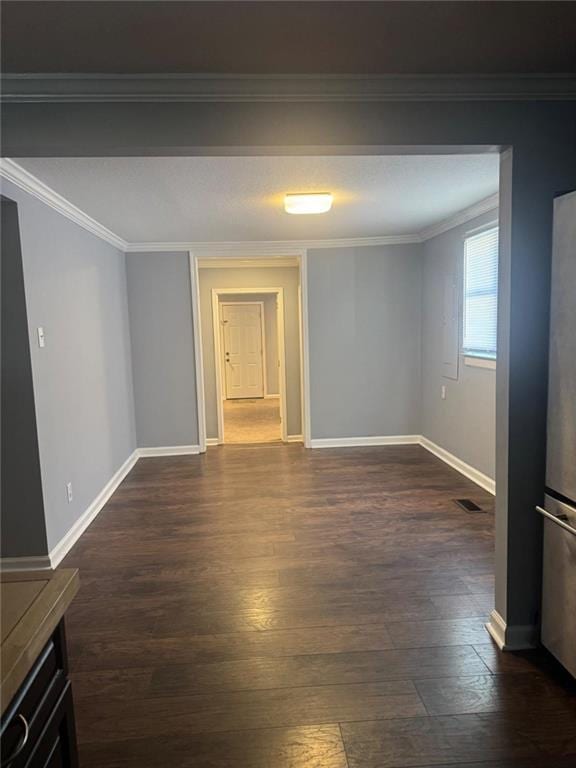 spare room with dark wood-type flooring, ornamental molding, and baseboards