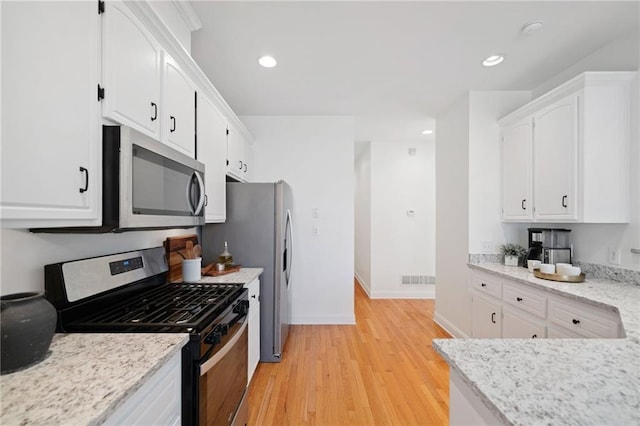 kitchen with light stone countertops, white cabinetry, appliances with stainless steel finishes, and light hardwood / wood-style flooring