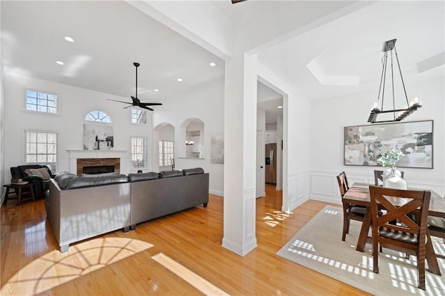 living room featuring a fireplace, ceiling fan with notable chandelier, and wood-type flooring