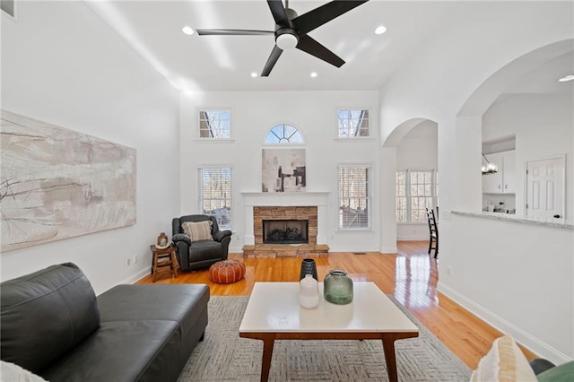 living room featuring hardwood / wood-style flooring, a stone fireplace, and a towering ceiling