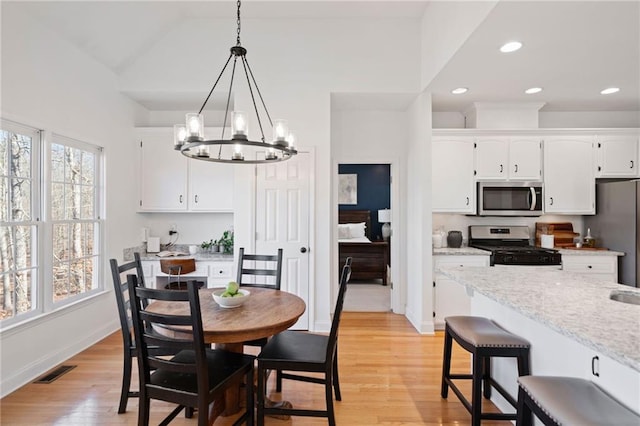 dining space with light hardwood / wood-style flooring, a notable chandelier, and vaulted ceiling