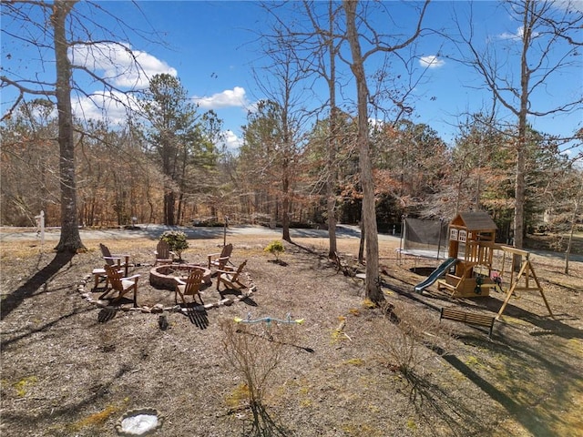 view of yard with a playground, a trampoline, and a fire pit