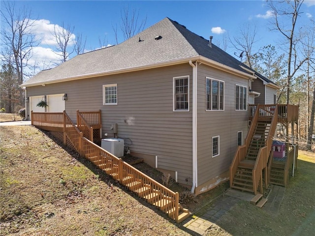 view of side of home with a garage, a wooden deck, and cooling unit