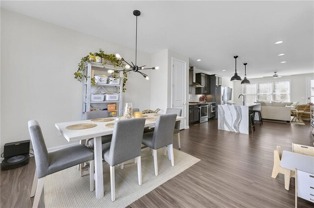 dining room with an inviting chandelier, recessed lighting, and dark wood-style floors