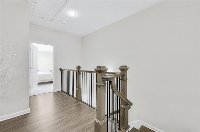 stairway with attic access, baseboards, and wood finished floors