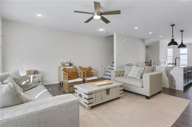 living room with stairway, a ceiling fan, wood finished floors, baseboards, and recessed lighting