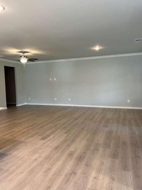 unfurnished room featuring ornamental molding, baseboards, wood finished floors, and a ceiling fan