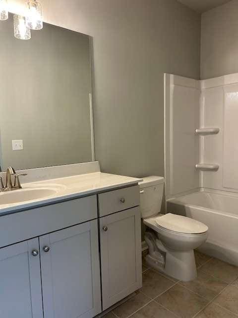 full bathroom featuring toilet, vanity, tile patterned floors, and  shower combination