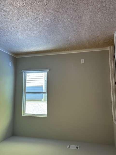 empty room with a textured ceiling and ornamental molding