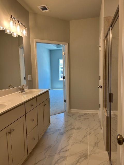 bathroom with marble look tile flooring, a stall shower, double vanity, and baseboards