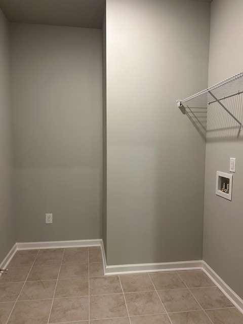 laundry area with hookup for a washing machine, light tile patterned floors, and baseboards