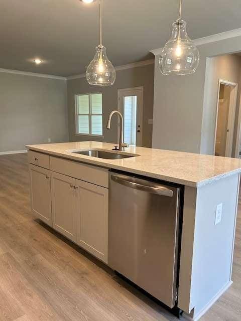 kitchen with stainless steel dishwasher, a sink, ornamental molding, a center island with sink, and light wood-style flooring