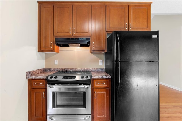 6752 Stringer Rd, Clermont, GA 30527 - kitchen with freestanding refrigerator, under cabinet range hood, stainless steel electric range oven, and brown cabinetry