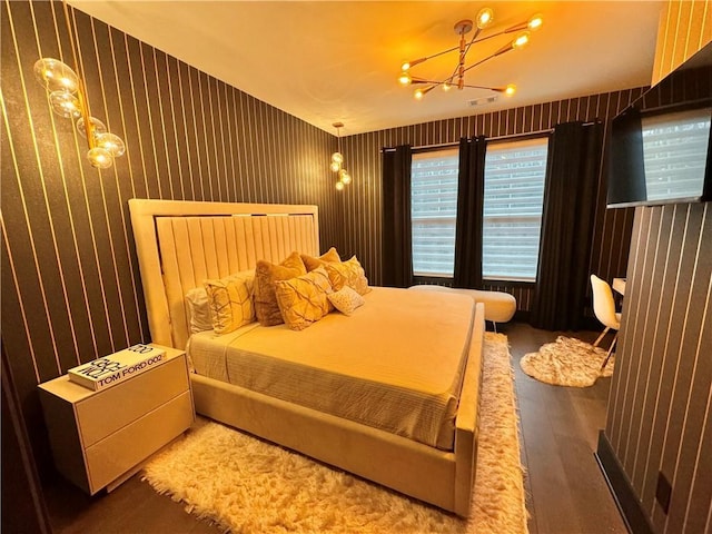 bedroom with hardwood / wood-style flooring and an inviting chandelier