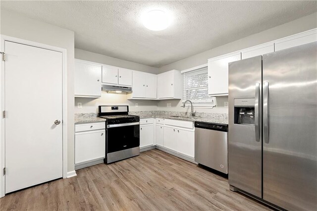 kitchen with stainless steel appliances, white cabinetry, sink, and light hardwood / wood-style flooring