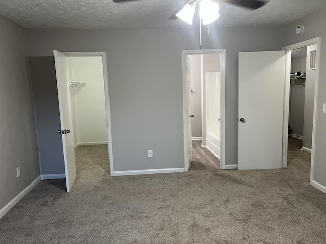 unfurnished bedroom with a spacious closet, a closet, light colored carpet, and a textured ceiling