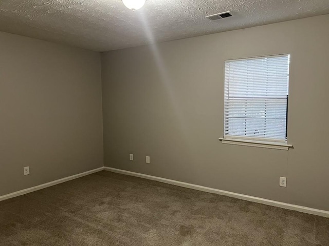 empty room with dark carpet and a textured ceiling