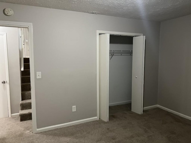 unfurnished bedroom featuring a textured ceiling, carpet floors, and a closet