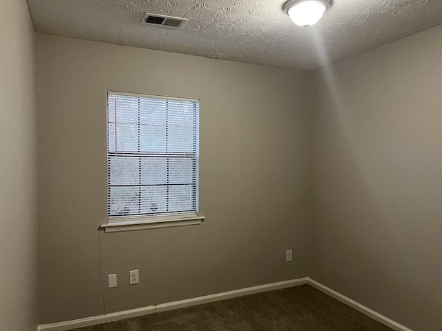 empty room with a textured ceiling and dark carpet