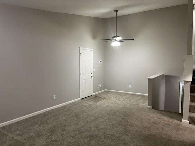 unfurnished living room featuring ceiling fan, carpet floors, and a towering ceiling