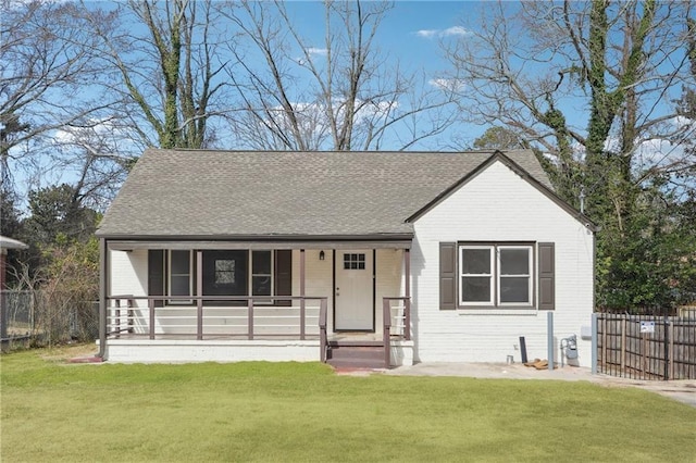 view of front of home featuring a porch, a front yard, roof with shingles, and fence