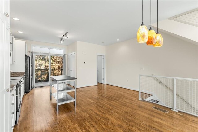 kitchen featuring rail lighting, appliances with stainless steel finishes, and dark wood-type flooring