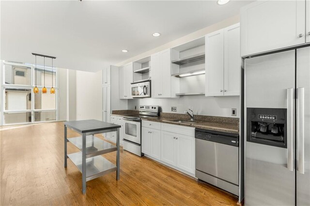 kitchen with sink, light hardwood / wood-style flooring, appliances with stainless steel finishes, light stone counters, and dark brown cabinetry