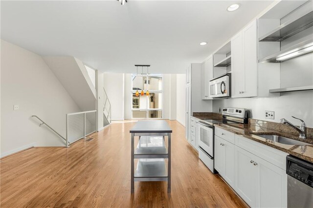 kitchen with dark brown cabinetry, sink, dark stone counters, stainless steel appliances, and light hardwood / wood-style floors