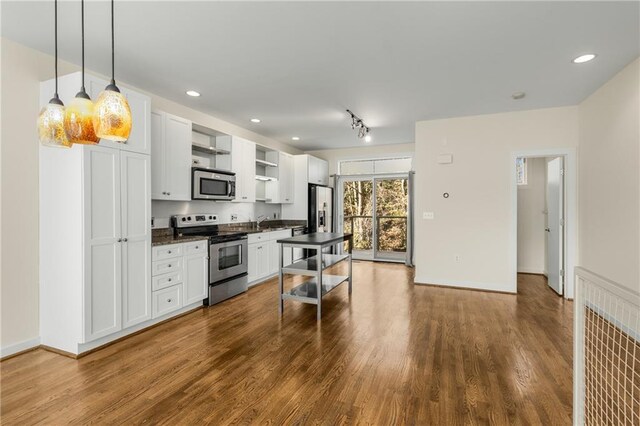 kitchen featuring stone counters, pendant lighting, sink, stainless steel appliances, and light wood-type flooring