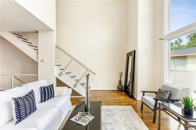 living room with hardwood / wood-style flooring, a towering ceiling, and a wealth of natural light