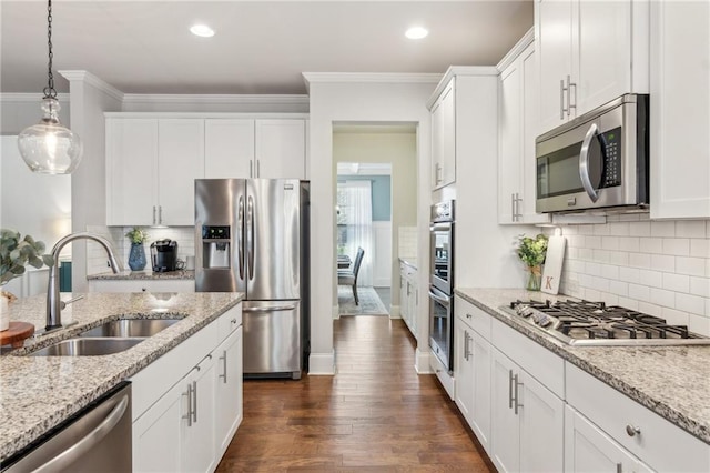 kitchen with white cabinetry, stainless steel appliances, light stone countertops, and sink