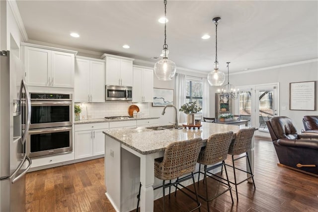 kitchen featuring sink, white cabinetry, a center island with sink, pendant lighting, and stainless steel appliances