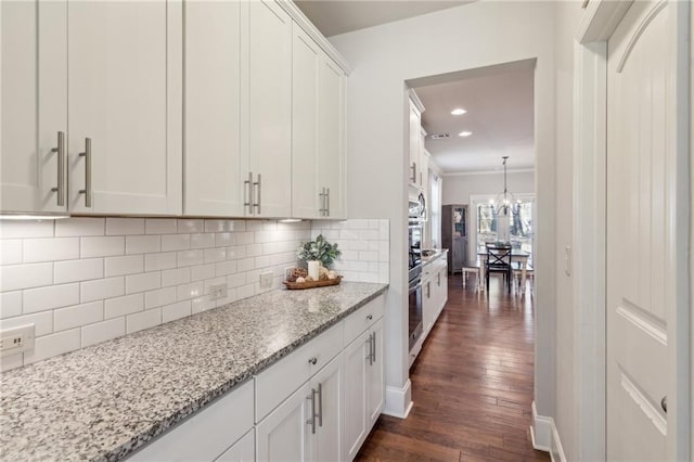 kitchen featuring backsplash, dark hardwood / wood-style flooring, white cabinets, light stone counters, and stainless steel appliances