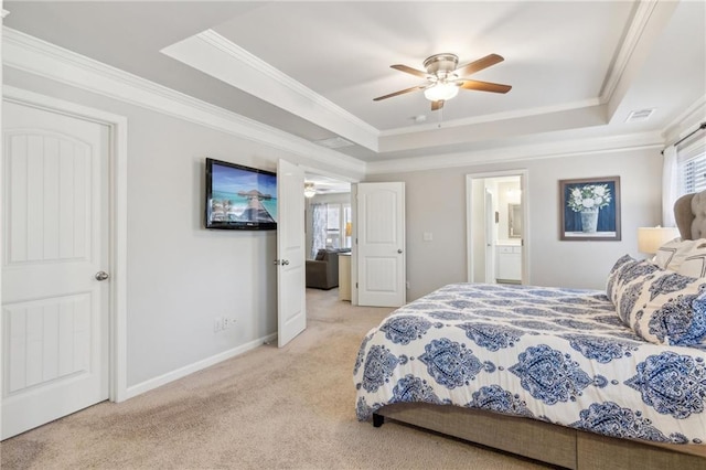 carpeted bedroom with a raised ceiling, crown molding, connected bathroom, and ceiling fan