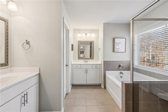 bathroom featuring tile patterned flooring, vanity, and tiled bath