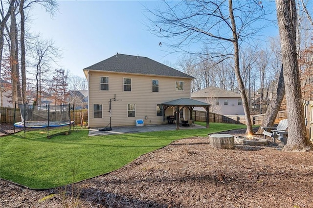 rear view of house with a patio, a fire pit, a lawn, a trampoline, and a gazebo