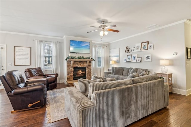 living room featuring crown molding, dark wood-type flooring, a stone fireplace, and ceiling fan