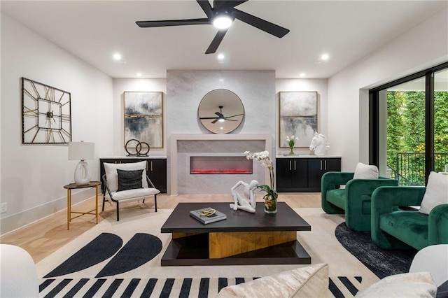 living room with ceiling fan, light wood-type flooring, and a high end fireplace