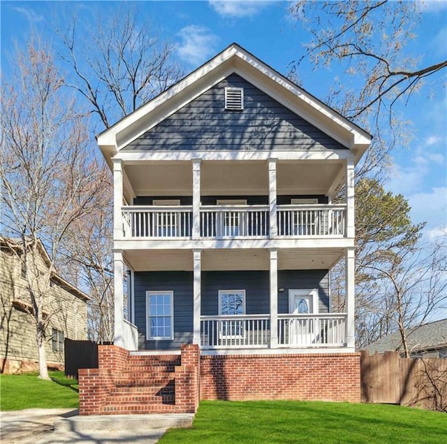 view of front of house with a balcony, fence, a porch, and a front yard