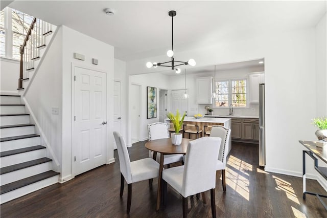 dining area featuring dark wood-style floors, stairway, a chandelier, and baseboards