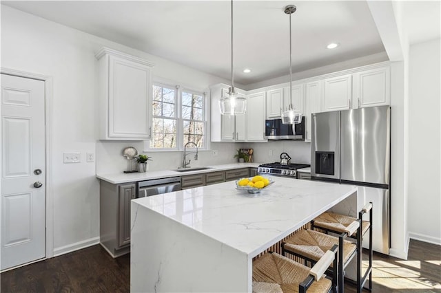 kitchen featuring dark wood-style flooring, stainless steel appliances, a sink, a kitchen island, and a kitchen breakfast bar