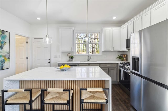 kitchen with appliances with stainless steel finishes, dark wood-style flooring, a sink, and white cabinetry