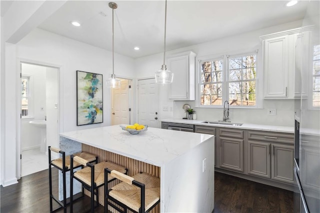 kitchen with dark wood finished floors, a kitchen island, a breakfast bar area, a sink, and recessed lighting