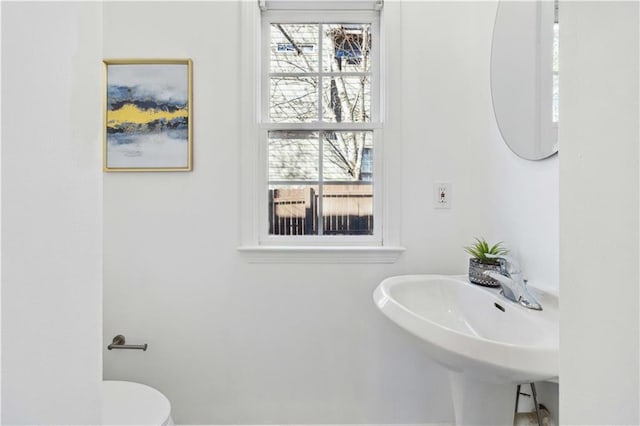 half bath with a wealth of natural light, a sink, and toilet