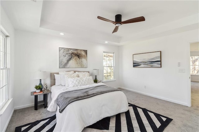 carpeted bedroom featuring ceiling fan, baseboards, a raised ceiling, and recessed lighting