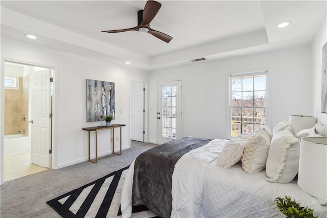 bedroom featuring carpet floors, multiple windows, and a raised ceiling